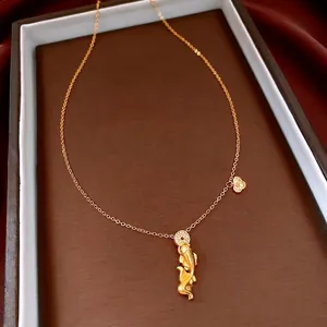 Golden koi fish pendant necklace with zircon bow accents on a premium leather display