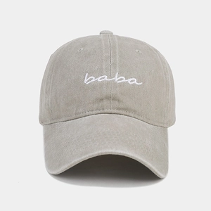 Detail of white baba letter embroidery on washed khaki cotton baseball cap fabric
