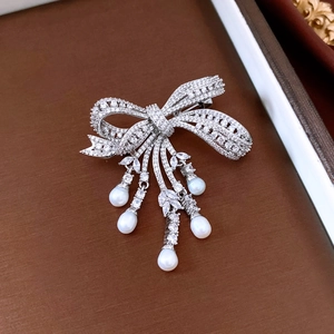 Macro view of zircon bow brooch with five hanging pearl tassels on a retro background