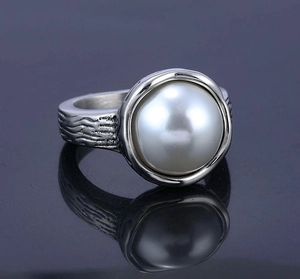Macro detail showing a large white pearl and bark-textured silver stainless steel ring band
