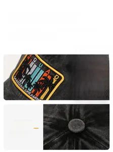 Detail of a washed black baseball cap featuring palm tree embroidery and top button seams