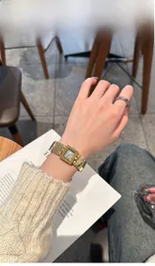 Élégante montre carrée dorée pour femme au poignet avec un pull en maille beige