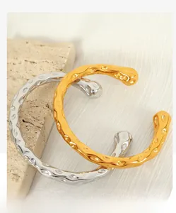 Detailed view of hammered gold and silver open bracelets on elegant stone background