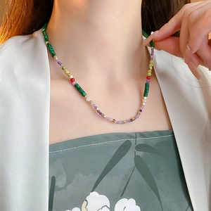 Close-up of handmade beaded necklace with green malachite and purple amethyst beads