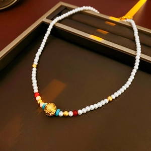 Gros plan sur collier de perles plaqué or 18k avec perles ajourées sur présentoir