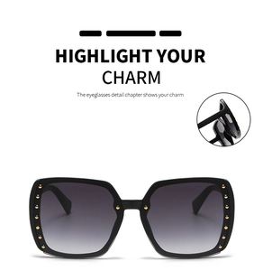 Detail view of large square sunglasses with gold rivets on black frame and gradient lenses