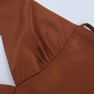 Détail de la poitrine froncée sur un haut licou en satin marron avec texture soie