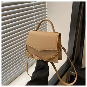 Detail of beige flap handbag with gold chain accent and crocodile embossed texture