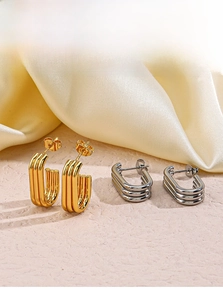 Detailed view of layered U-shaped gold and silver earrings on elegant silk background