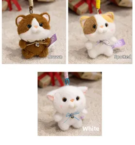 Detailed view of plush cat keychains in brown, spotted and white with heart bells