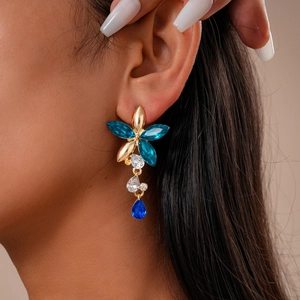 Gros plan détaillé de boucles d'oreilles fleurs vintage avec strass bleus sur modèle