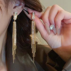 Detail of long gold tassel earrings with rectangular zircons and fine metal bead chains
