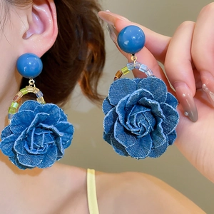 Détail des boucles d'oreilles rose en denim avec perles colorées et tiges en argent