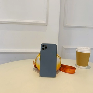 Detail of dark grey silicone phone case and cartoon smiley round bag on a round table