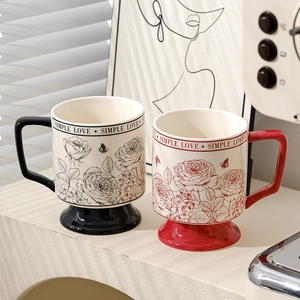 Detail of red and black ceramic mugs featuring rose and butterfly patterns with Simple Love text