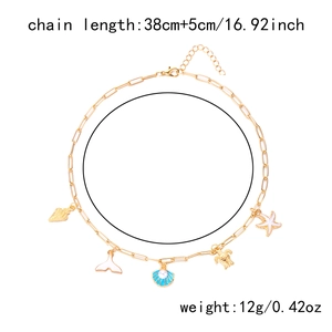 Detail of gold necklace with seashell, starfish and turtle charms on a white background