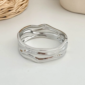 Macro detail of silver wide cuff bracelet with deconstructed wavy texture and irregular shape