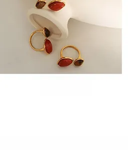 Detail of bohemian gold ring featuring red agate and tiger eye stones in a warm scene