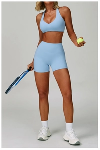Detail of light blue V-neck sports bra and high-waisted shorts set with a tennis racket
