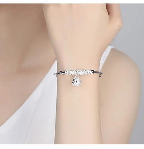 Close-up of silver-plated bracelet featuring hollow bell charms and patterned lucky beads