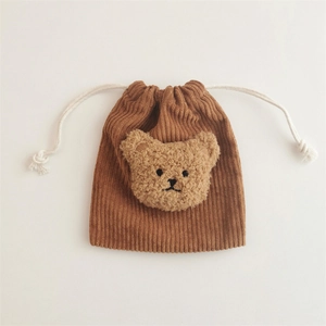 Close-up of brown corduroy drawstring pouch with a cute plush bear head decoration