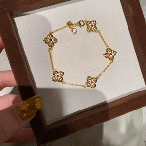Detailed macro view of 14k gold plated four-leaf clover bracelet with red stones