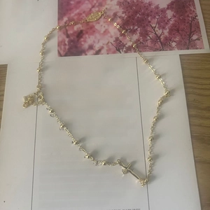 Detail of 14K gold plated bead chain necklace with cross pendant and religious medal