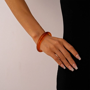 Detail shot of a translucent amber acrylic open bangle with polished resin texture