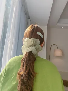 Macro detail of mint green organza hair scrunchie with subtle shimmer on ponytail