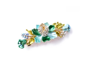 Detail of floral enamel hair clip with blue rhinestones and gold-tone metal frame