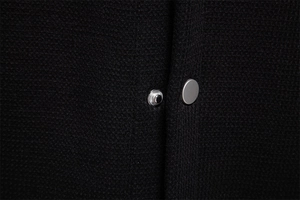 Detail of waffle knit jacket showing black fabric texture and premium metal snap button