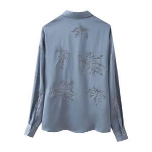 Detailed embroidery and beadwork on the back of this blue satin long-sleeved shirt