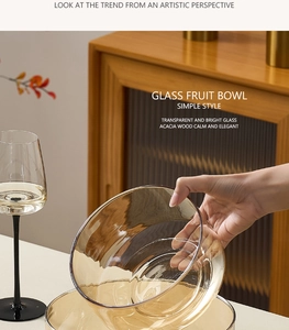 Detailed view of amber glass fruit bowl held by hand with elegant wooden stand