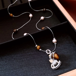 Close-up of tiger eye stone necklace with a crystal rocking horse pendant on black velvet