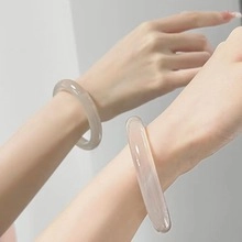 Close-up of translucent sky blue chalcedony bangles on wrists with smooth circular design