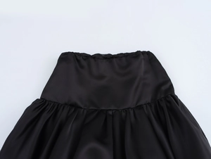 Detailed macro view of the black satin skirt's elastic waistband and fine pleated texture
