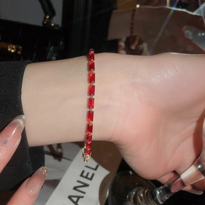 Macro detail of luxury 18k gold ruby bracelet with red gemstones on female wrist
