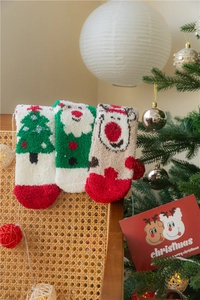 Chaussettes de Noël duveteuses aux motifs de Père Noël et rennes dans un décor cosy