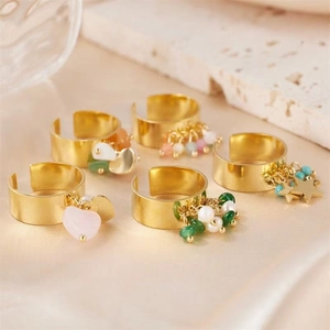 Detail of gold-plated adjustable rings with colorful stones and charms on silk and marble