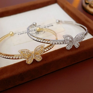 Macro shot of gold butterfly open cuff bracelet with cubic zirconia inlay on velvet