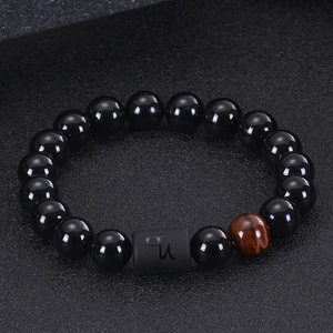 Macro detail of zodiac beaded bracelet with black agate, tiger eye and Capricorn charm