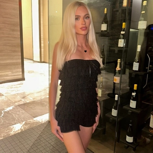 Close-up of black lace tiered strapless romper on model in luxury wine cellar setting