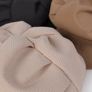 Gros plan sur la texture gaufrée beige et les détails plissés de cette casquette