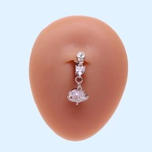 Detailed view of silver heart-shaped navel ring with transparent crystal on skin-tone model