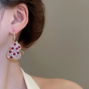 Detailed close-up of a gold gourd drop earring featuring red zircons and pavé diamonds