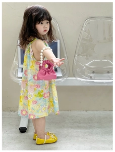 Pink mini handbag with pearl handle and pleated design held by girl in floral dress