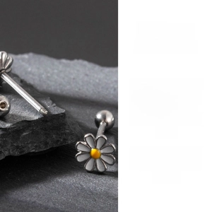 Détail de bijoux de langue marguerite avec émail blanc sur une surface de roche noire