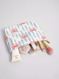 Borsa per cosmetici in tela a righe blu e fiocchi rosa con vari prodotti di bellezza