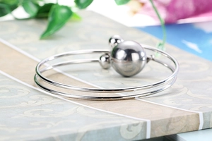 Detail view of silver double-loop stainless steel bracelet with polished ball charms
