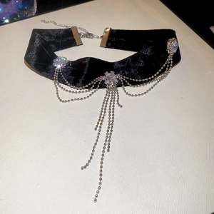 Détail d'un choker en velours noir avec franges de chaîne argentée et strass brillants